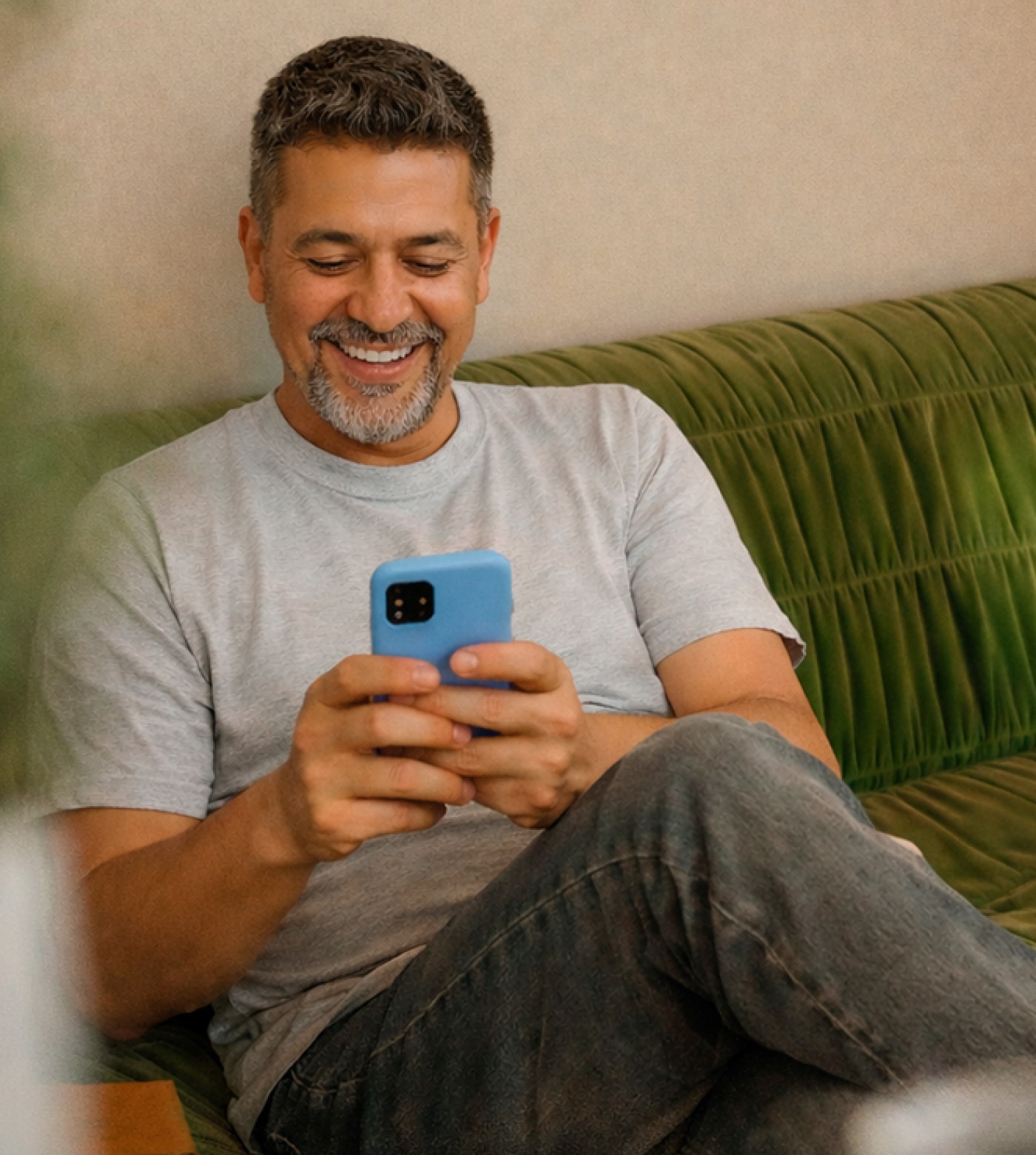 Man on couch smiling while looking at his phone