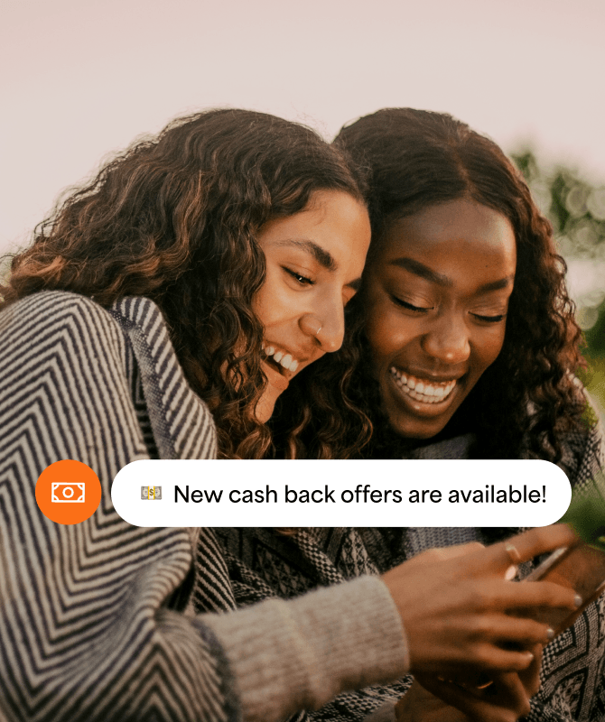Two women looking at their phone with a cash back offers notification.